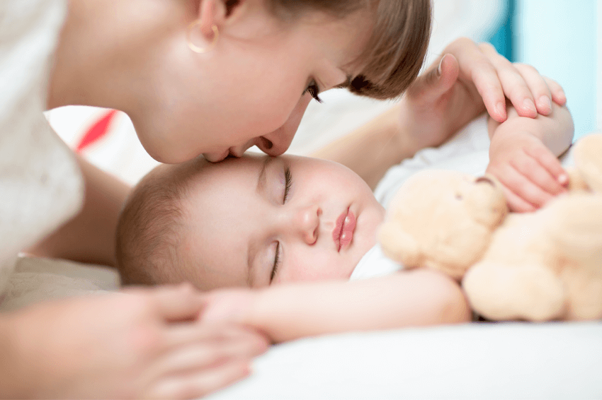 Woman kissing sleeping infant