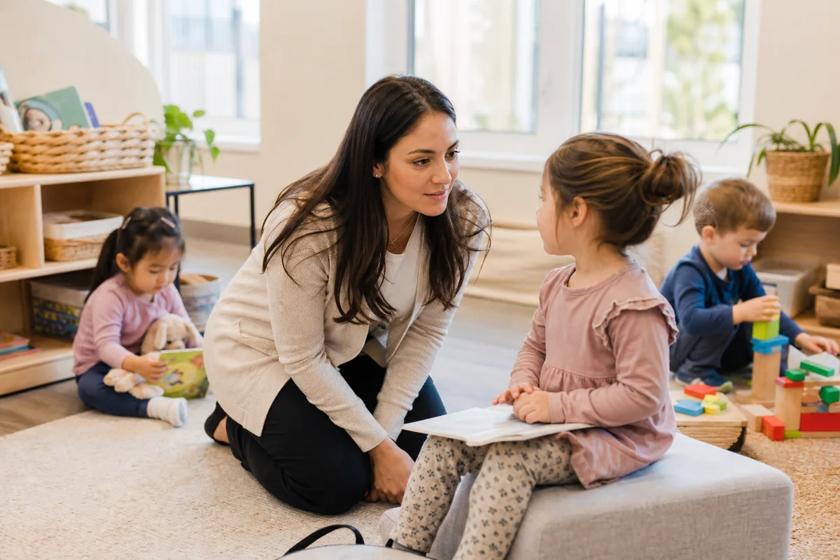 Daycare educator listening to a preschool child at eye level