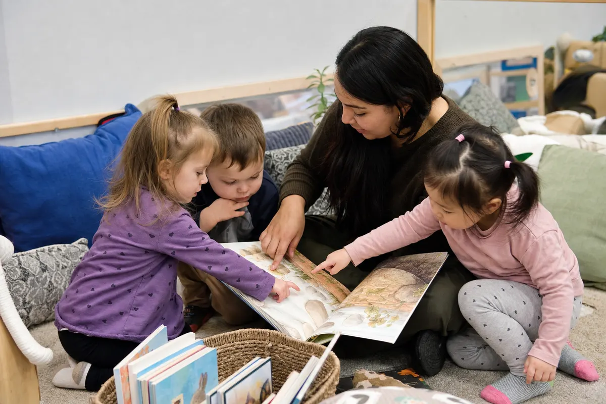 Daycare educator and toddlers talking about pictures in a book