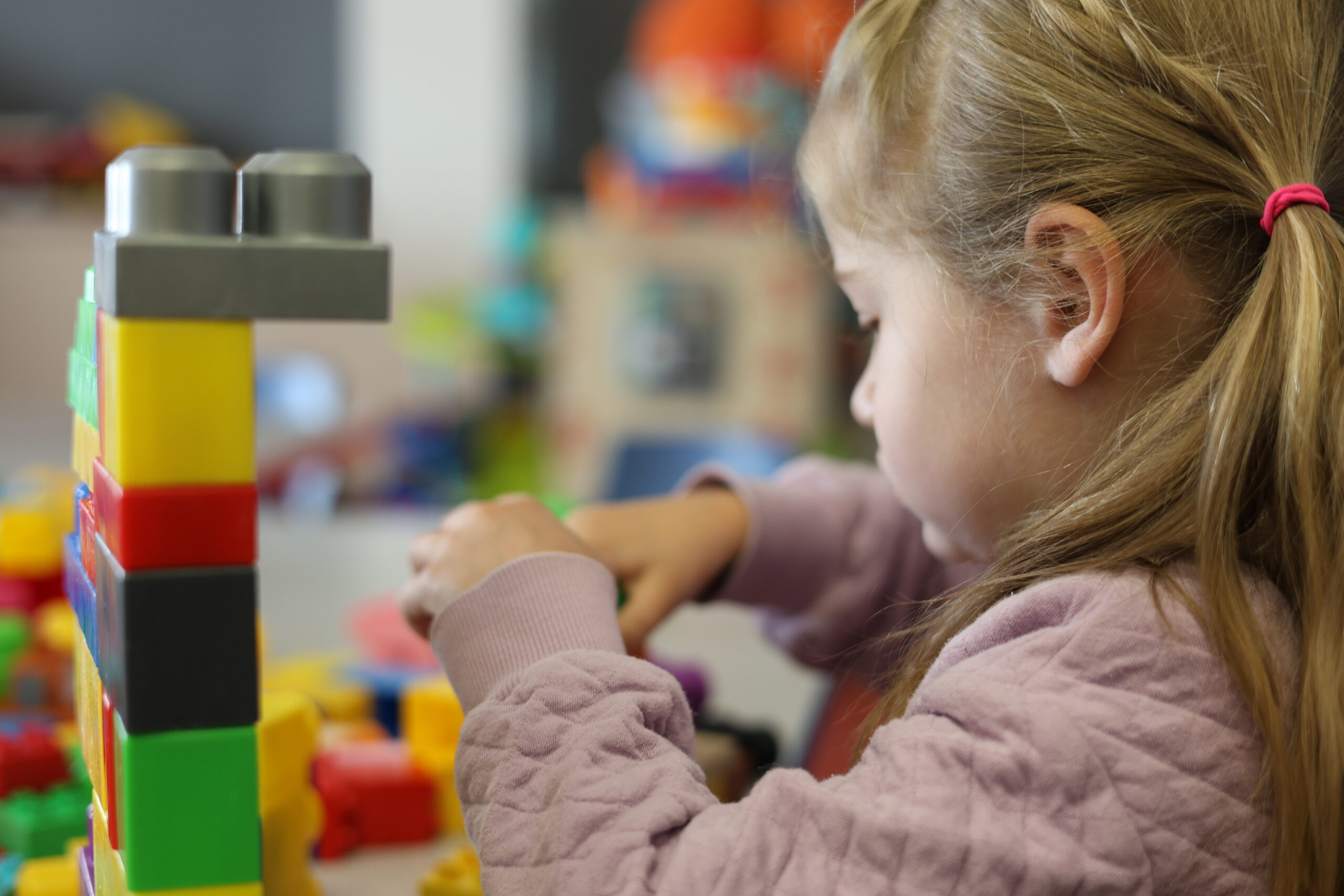 A child concentrating on blocks beside a colourful block structure